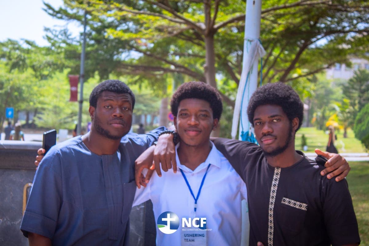 Three friends standing arm in arm outdoors