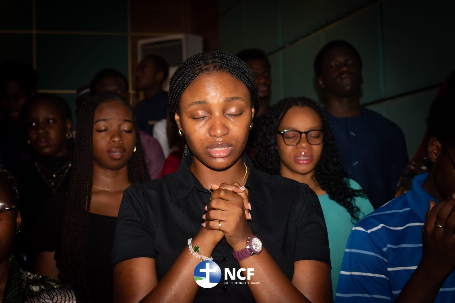 A student praying with clasped hands during a gathering