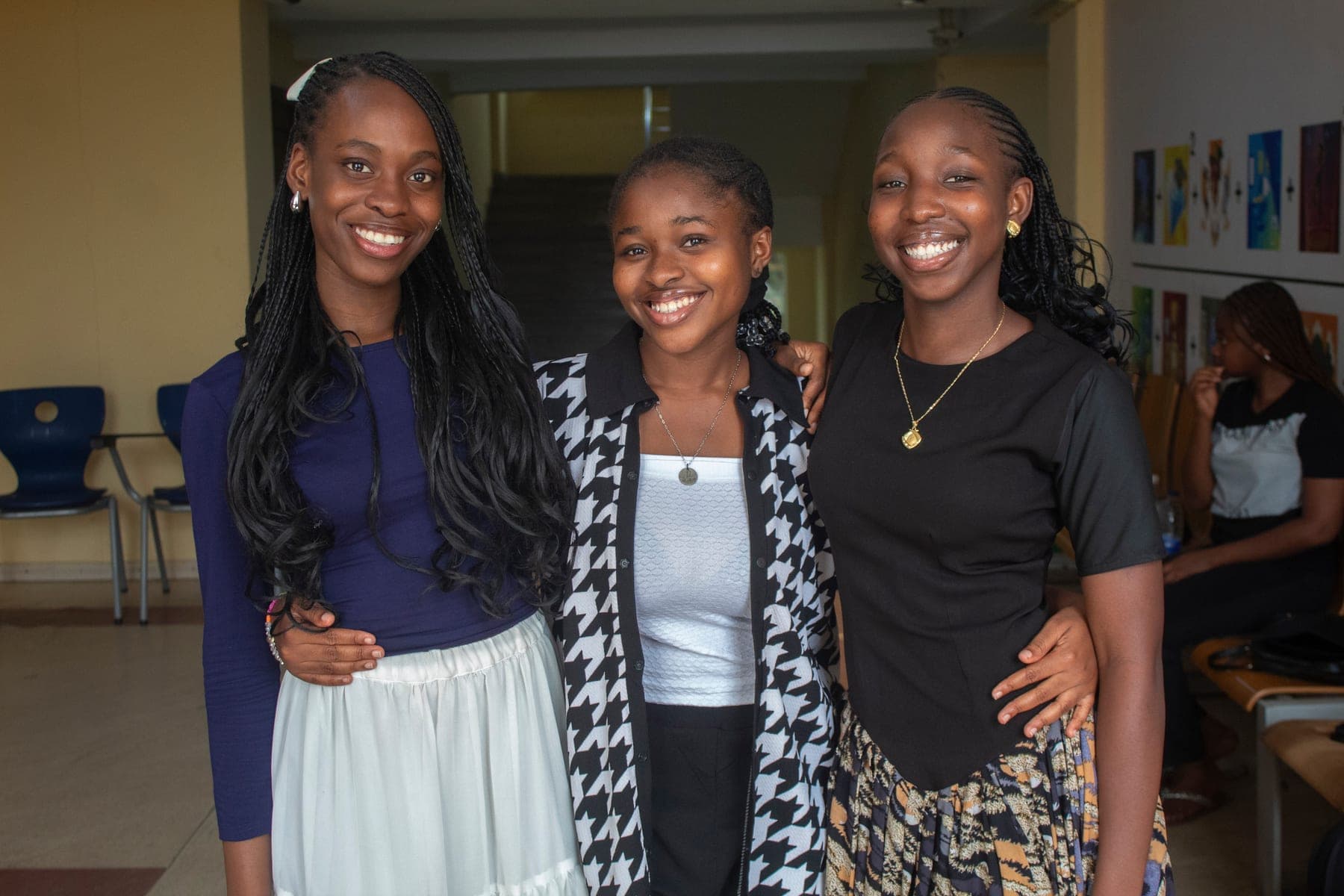 Three students smiling together in a campus corridor