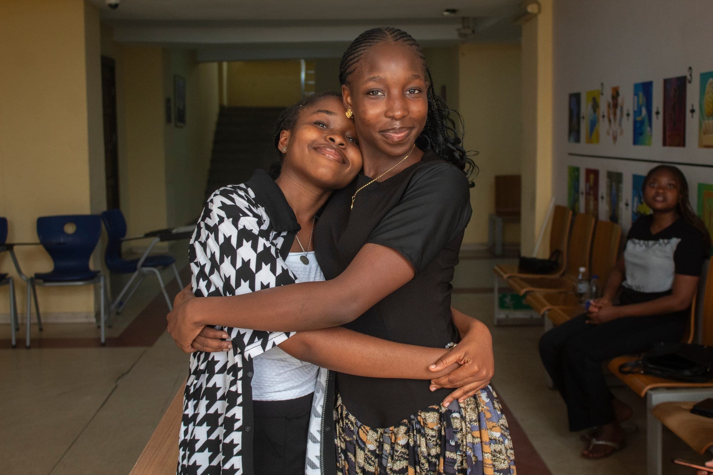 Two students embracing warmly in a campus hallway