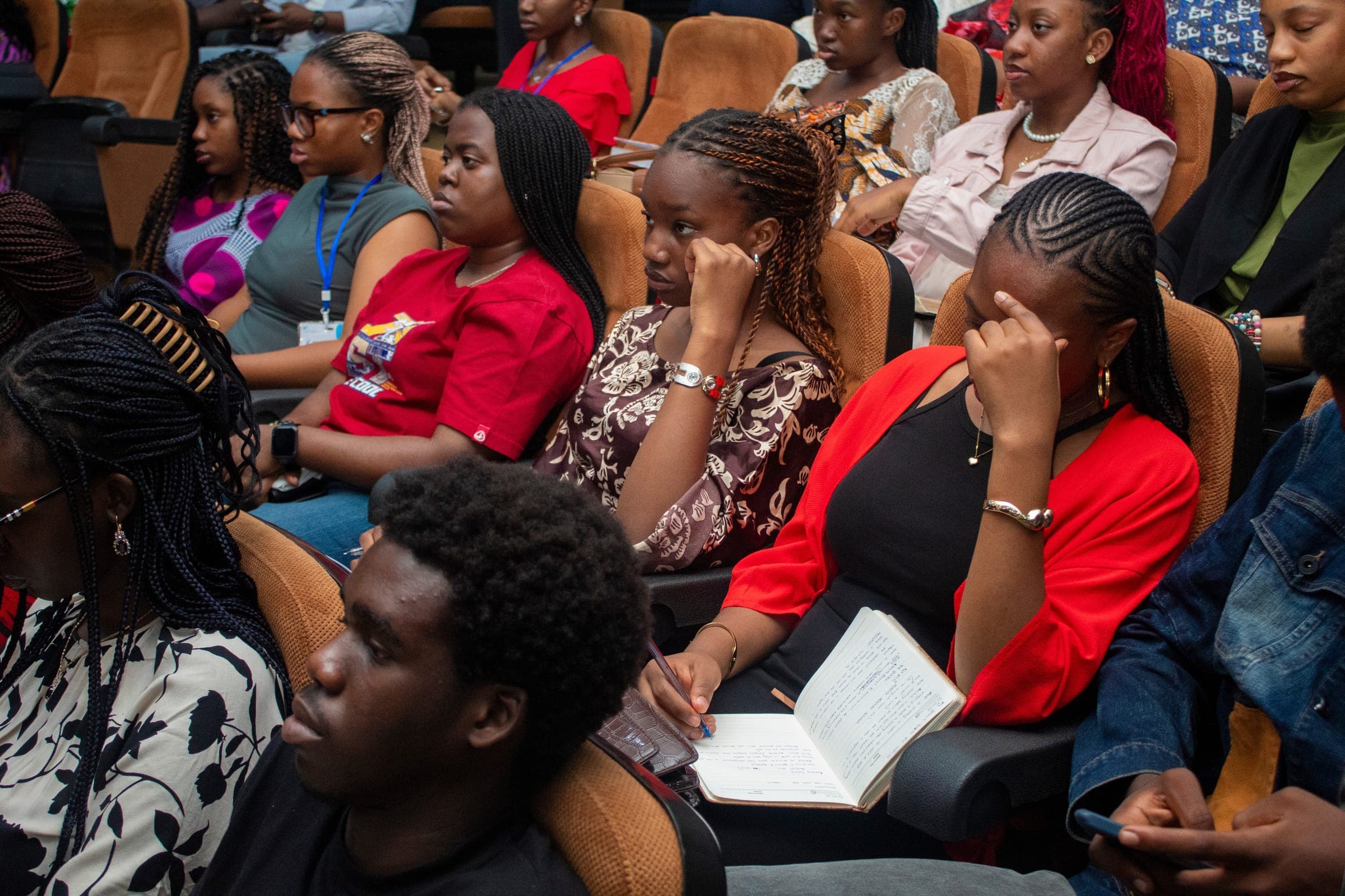 Students seated together, one taking notes during a message